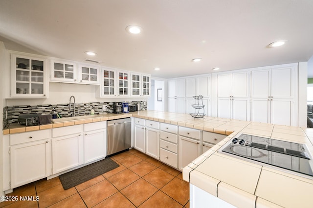 kitchen featuring a sink, tile counters, stainless steel dishwasher, and white cabinetry