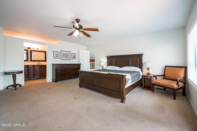 bedroom with light carpet, ensuite bathroom, and a ceiling fan
