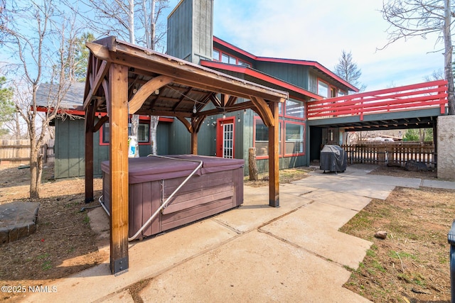 view of patio featuring a gazebo, grilling area, fence, and a hot tub