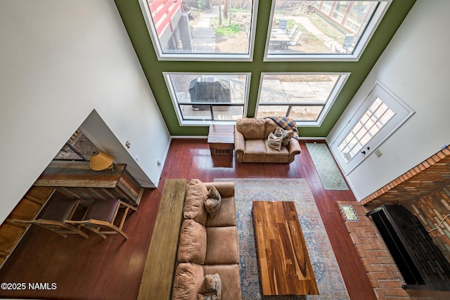 living area with a wealth of natural light, a high ceiling, baseboards, and wood finished floors