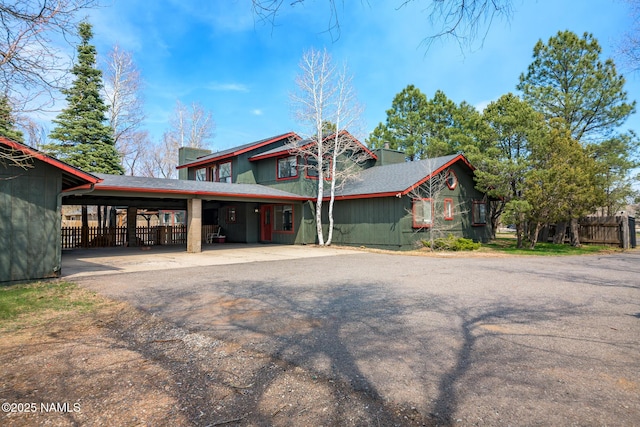 chalet / cabin featuring a carport, aphalt driveway, and fence