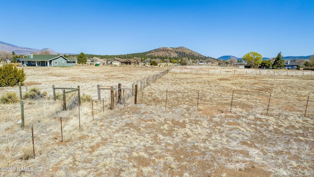 view of yard featuring fence, a mountain view, and a rural view