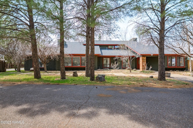 view of front facade with roof with shingles and a chimney