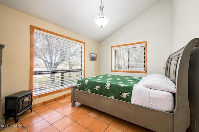 bedroom featuring a wood stove, high vaulted ceiling, and tile patterned flooring