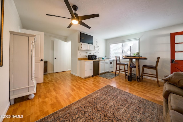 kitchen with baseboards, black microwave, a ceiling fan, white cabinets, and light wood finished floors