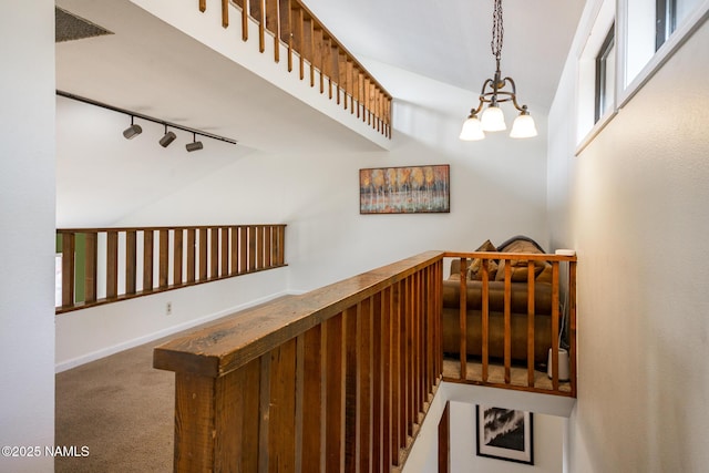 stairway featuring an inviting chandelier, a bar, carpet floors, vaulted ceiling, and rail lighting