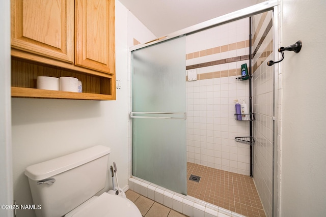 bathroom with toilet, tile patterned flooring, and a stall shower