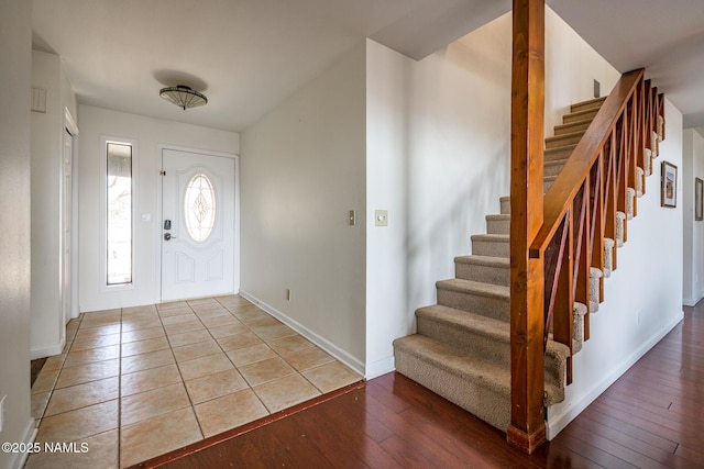 foyer with wood-type flooring, baseboards, and stairs