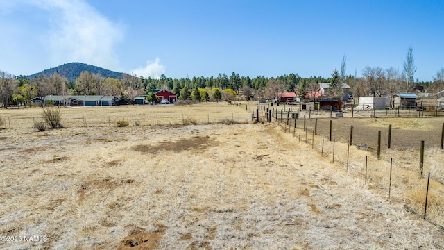 view of yard featuring a rural view, a mountain view, and fence