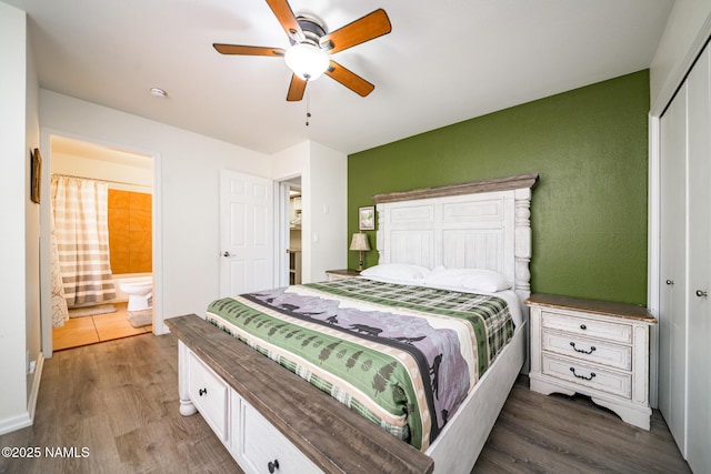 bedroom with ensuite bath, ceiling fan, a closet, and wood finished floors