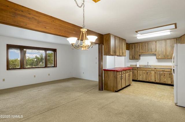 5920 Wildflower Rd, Flagstaff, AZ 86004 - kitchen with a chandelier, hanging light fixtures, a sink, freestanding refrigerator, and brown cabinetry
