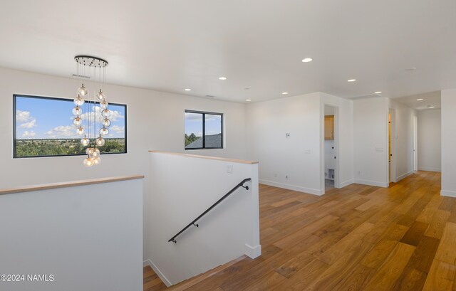 hall featuring wood-type flooring, a wealth of natural light, and a chandelier