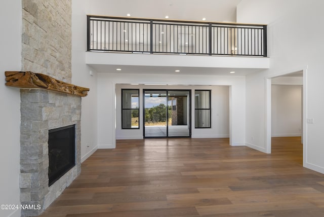 unfurnished living room with a towering ceiling, hardwood / wood-style floors, and a fireplace