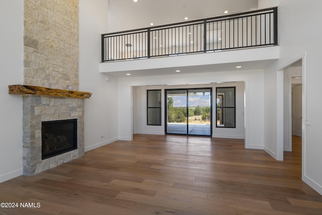 unfurnished living room featuring hardwood / wood-style flooring, a towering ceiling, and a fireplace