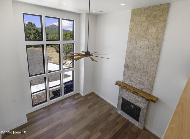 unfurnished living room with ceiling fan, dark wood-type flooring, and a fireplace