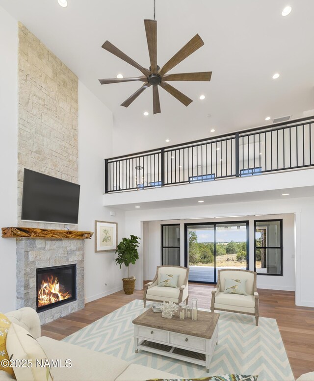 kitchen featuring light hardwood / wood-style floors, appliances with stainless steel finishes, wall chimney range hood, backsplash, and light stone counters