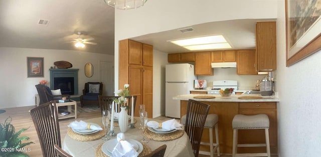 kitchen with under cabinet range hood, light countertops, visible vents, freestanding refrigerator, and gas range