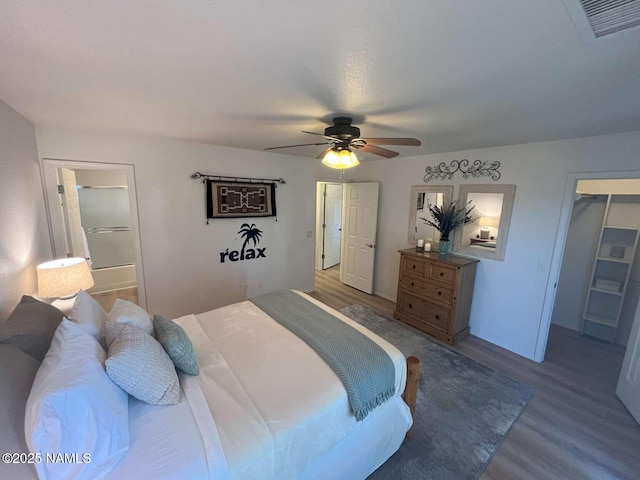 bedroom with connected bathroom, ceiling fan, wood finished floors, and visible vents