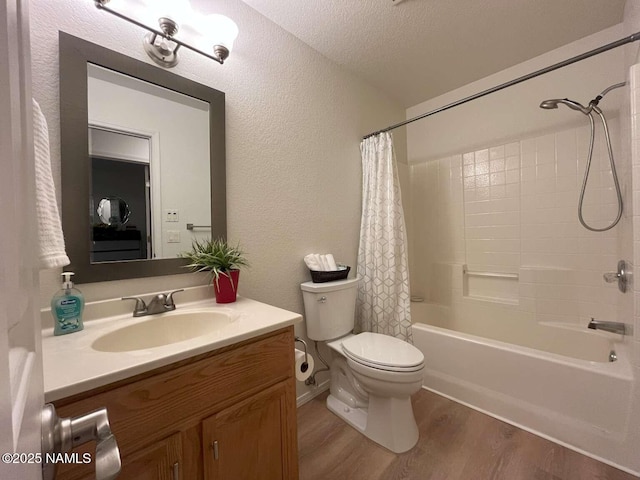 bathroom with shower / bath combo, wood finished floors, vanity, a textured wall, and toilet