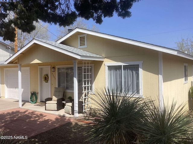 view of front of property featuring an attached garage and a shingled roof