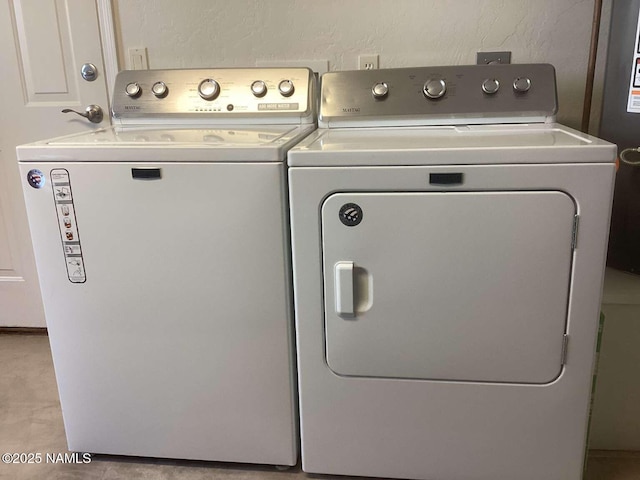 clothes washing area with a textured wall, laundry area, and independent washer and dryer