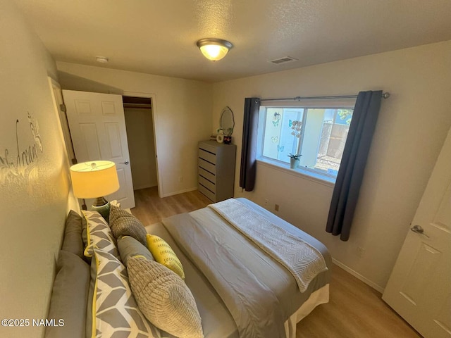 bedroom featuring a textured ceiling, wood finished floors, visible vents, and baseboards