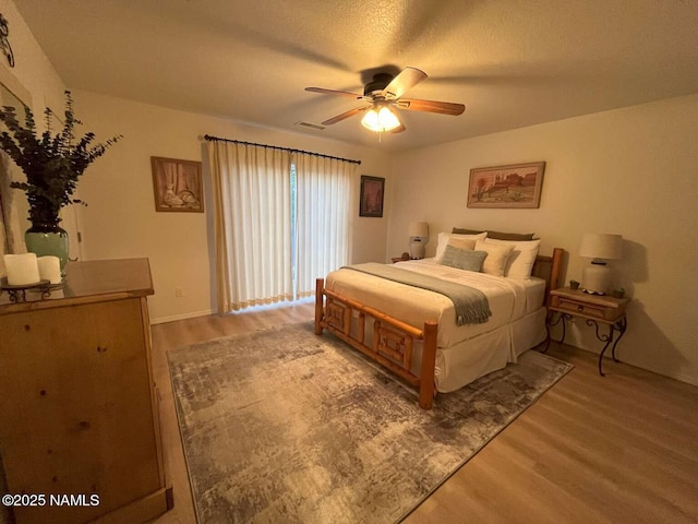 bedroom with ceiling fan, baseboards, and light wood-type flooring