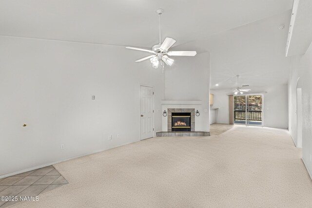 unfurnished living room featuring ceiling fan, lofted ceiling, light carpet, and a tiled fireplace