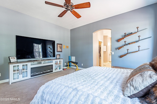 1533 S Minstrel Ln, Williams, AZ 86046 - carpeted bedroom with arched walkways, a glass covered fireplace, ceiling fan, and ensuite bathroom