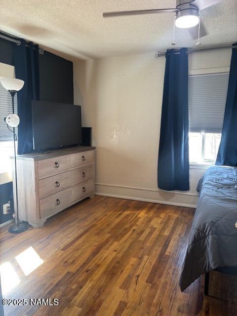 bedroom with a textured ceiling, ceiling fan, wood finished floors, and baseboards