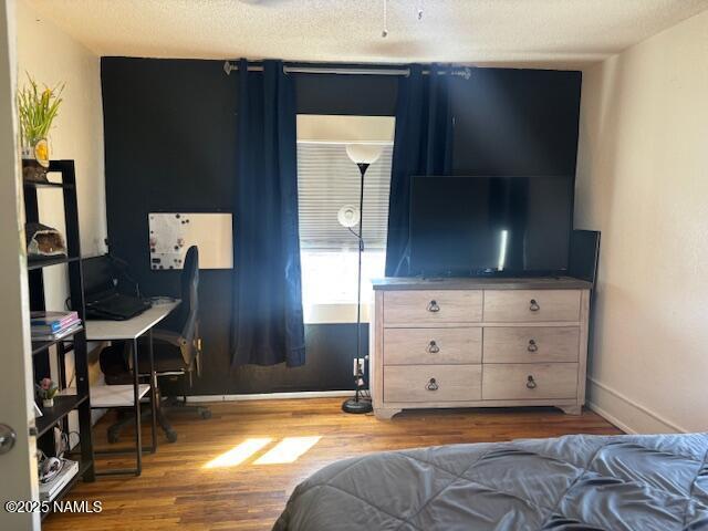 bedroom featuring a textured ceiling, baseboards, and wood finished floors