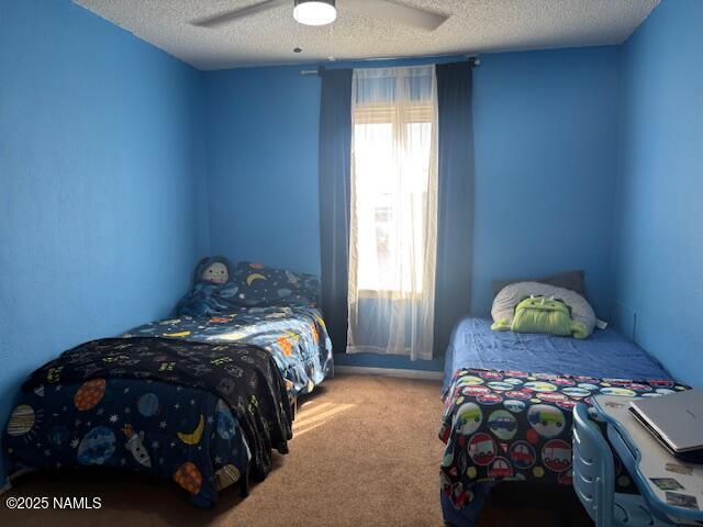 carpeted bedroom with ceiling fan and a textured ceiling