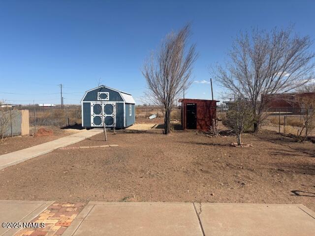 view of yard with a storage shed, an outbuilding, and fence