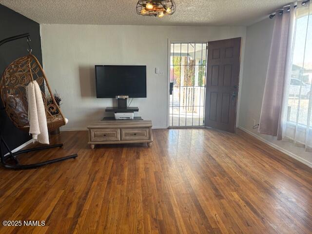 living room featuring a textured ceiling, wood finished floors, and baseboards