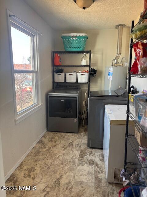 laundry area featuring water heater, a textured ceiling, separate washer and dryer, laundry area, and baseboards