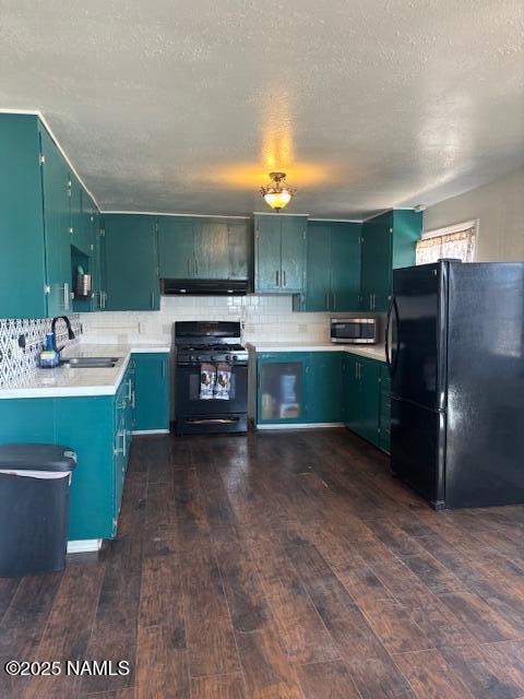 kitchen with dark wood-style floors, light countertops, a sink, under cabinet range hood, and black appliances