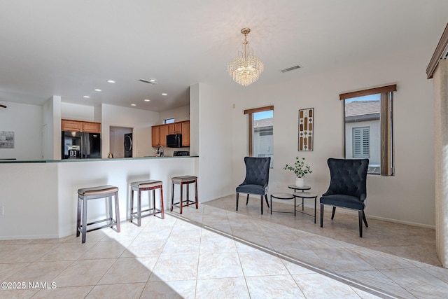 kitchen featuring light tile patterned flooring, a chandelier, kitchen peninsula, pendant lighting, and black appliances