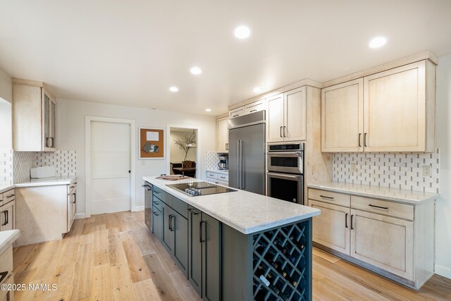 1451 N Mariposa Rd, Flagstaff, AZ 86004 - kitchen featuring appliances with stainless steel finishes, tasteful backsplash, a kitchen island, light wood-style flooring, and light stone countertops