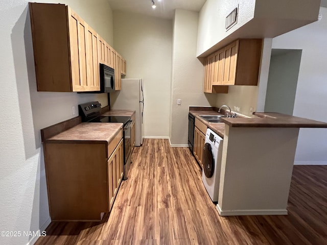 1185 W University Dr Unit 15-222, Flagstaff, AZ 86001 - kitchen with black appliances, washer / clothes dryer, light wood-style floors, dark countertops, and a peninsula