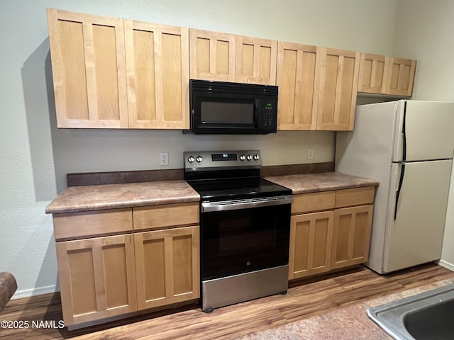 1185 W University Dr Unit 15-222, Flagstaff, AZ 86001 - kitchen featuring black microwave, stainless steel electric range, freestanding refrigerator, light brown cabinetry, and light wood-style floors