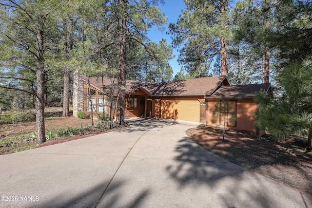 view of front facade with a garage, concrete driveway, and roof with shingles