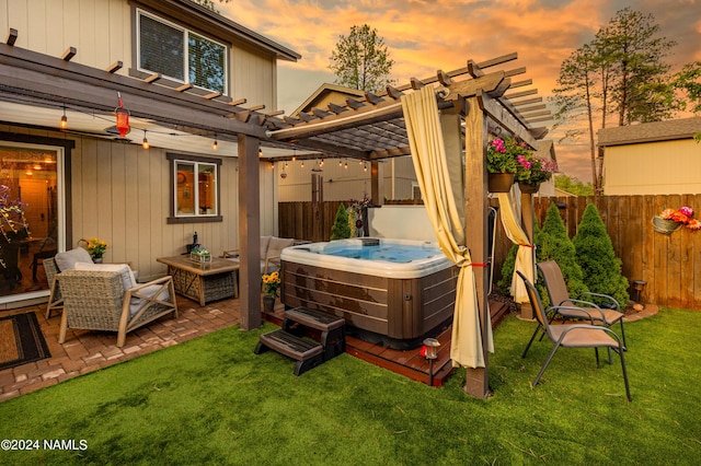 patio terrace at dusk featuring a yard, a pergola, and a hot tub