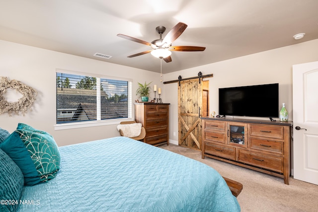 bedroom with light colored carpet, a barn door, and ceiling fan