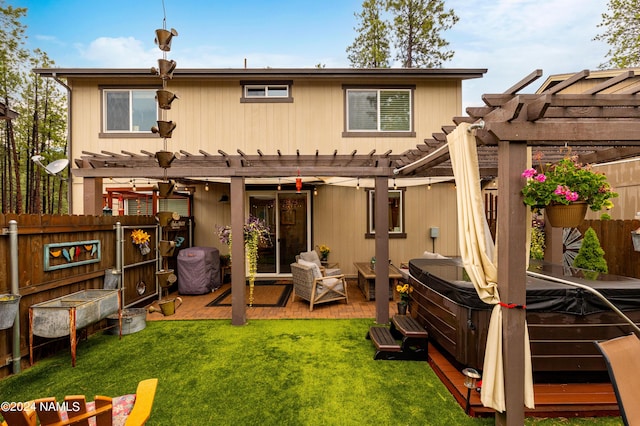 back of house with a hot tub, a wooden deck, a lawn, and a pergola