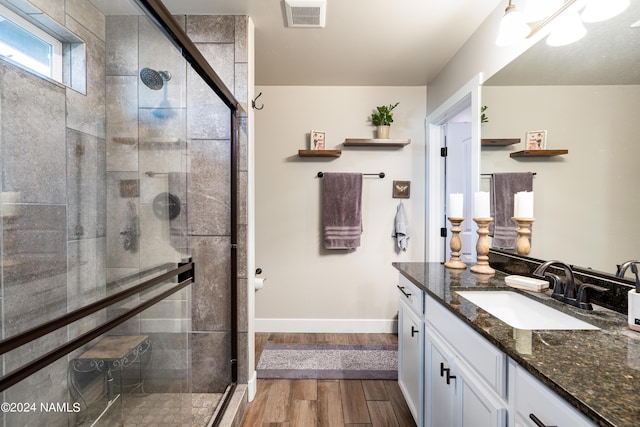 bathroom with an enclosed shower, vanity, and wood-type flooring