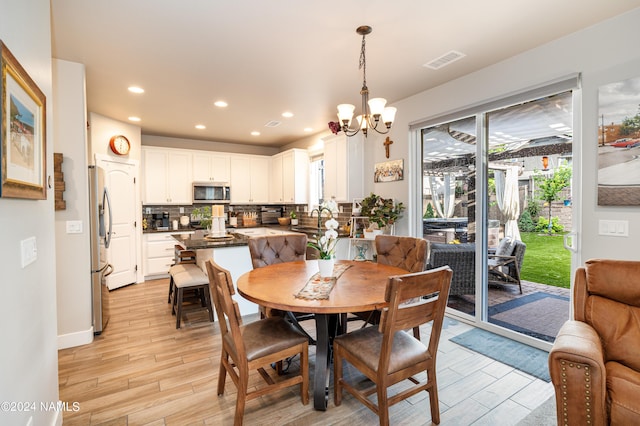 dining area featuring sink, a notable chandelier, and light hardwood / wood-style flooring