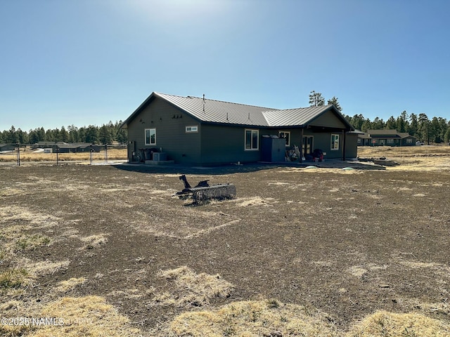 rear view of property featuring metal roof, central AC unit, a standing seam roof, and fence