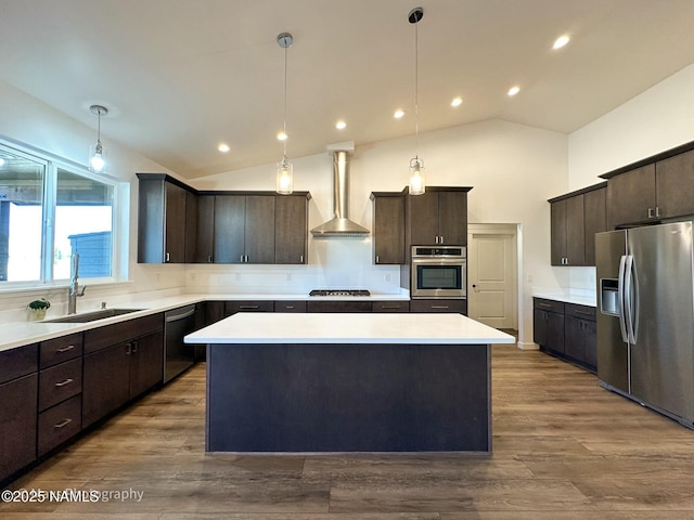 kitchen with a center island, stainless steel appliances, dark brown cabinetry, a sink, and wall chimney exhaust hood