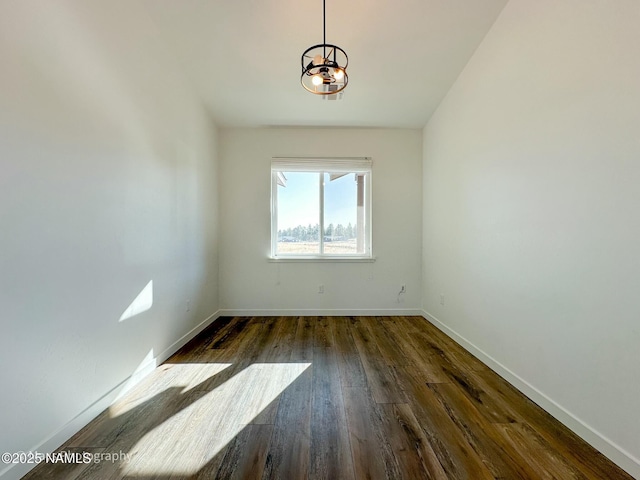 spare room featuring baseboards and dark wood-style flooring