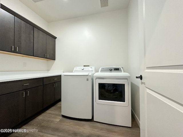 laundry area featuring wood finished floors, visible vents, cabinet space, and separate washer and dryer